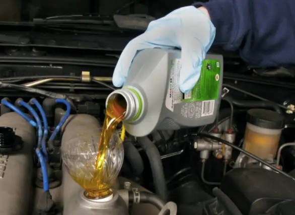 Photo of mechanic putting power steering fluid into the power steering reservoir.